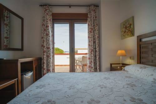 Bright double bedroom at Alojamientos Carolina y Vanesa with bed, terrace doors, floral curtains, and city views in San José,