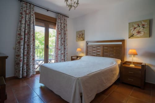 Double bedroom at Alojamientos Carolina y Vanesa in Níjar with wooden bed, balcony access, and city views