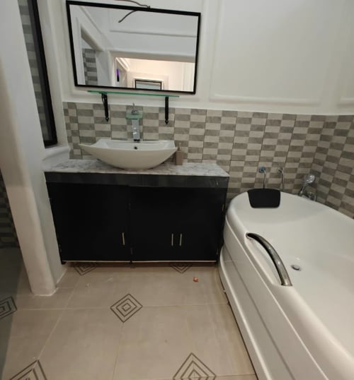Salle de bain moderne de la Mini-suite F4 à la Résidence hôtelière Ôkèrè Ôburu, Lomé avec vasque, miroir et baignoire