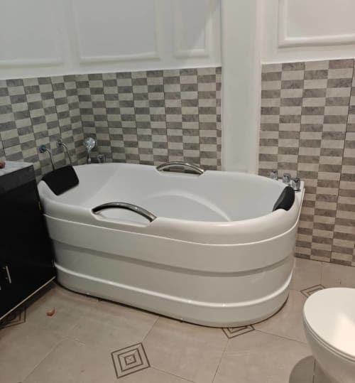 Baignoire blanche moderne dans la salle de bains de la suite supérieure F4 à la Résidence hôtelière Ôkèrè Ôburu, Lomé