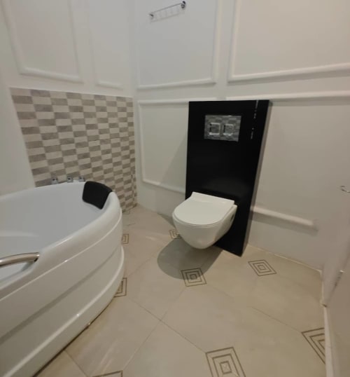 Salle de bains moderne de la Mini-suite supérieure F4 à la Résidence hôtelière Ôkèrè Ôburu, Lomé avec baignoire et toilettes murales