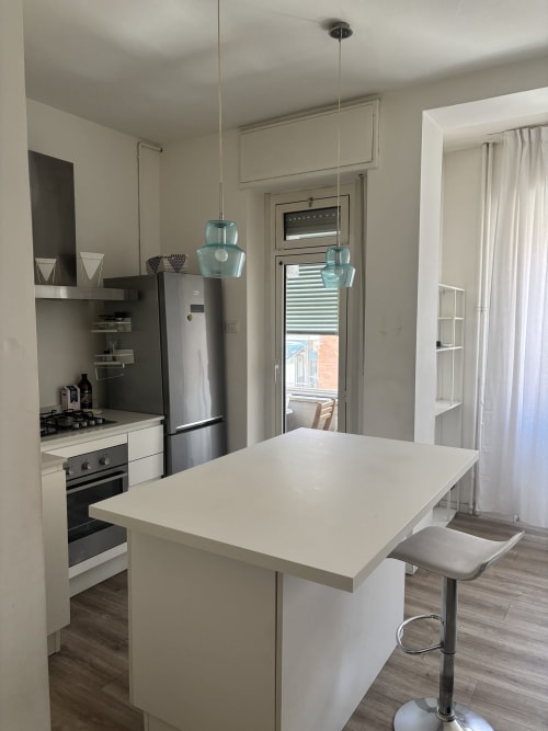Modern kitchen with island in Milano Underground apartment, featuring stainless steel appliances and white cabinetry