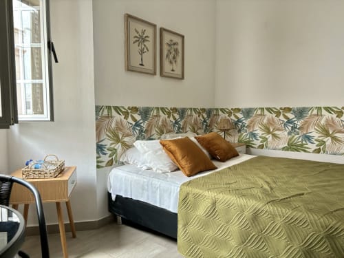 Quarto moderno do hotel Al Mare Ocean View em Albufeira com cabeceira estampada tropical, roupa de cama verde e arte com palmeiras
