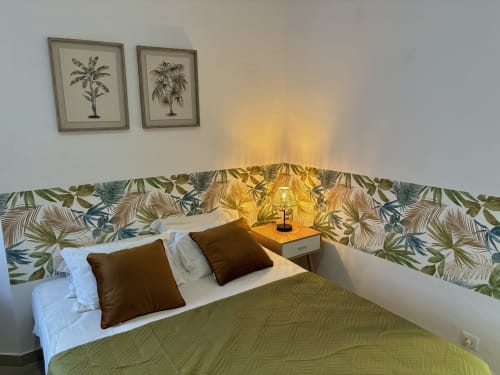 Quarto com tema tropical no hotel Al Mare Ocean View em Albufeira, com obra de arte de palmeiras e cabeceira com folhagens