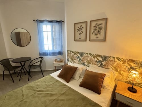 Quarto aconchegante de hotel em Albufeira com cama, mesa, obras de arte com palmeiras e vista para a cidade
