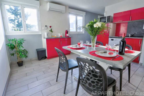 Cuisine-séjour moderne rouge et gris dans l'Appart'Hôtel Cholet avec vue sur le jardin