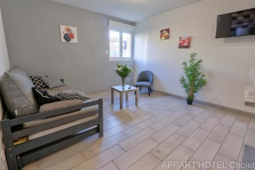Séjour moderne à l'Appart'Hôtel Cholet avec canapé-lit, fauteuil, kitchenette et carrelage