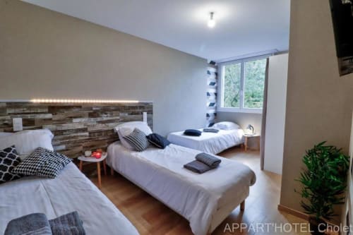 Appartement 2 chambres moderne à l'Appart'Hôtel Cholet avec lits jumeaux, tête de lit en bois, vue sur jardin et design contemporain