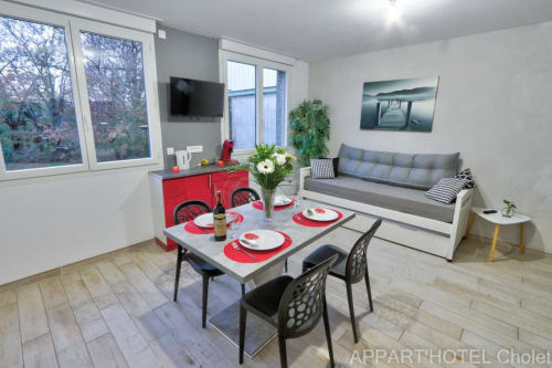 Studio moderne à l'Appart'Hôtel Cholet avec table à manger, kitchenette, canapé et grandes fenêtres