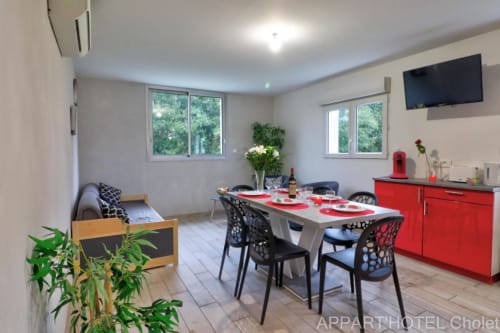 Appartement moderne 3 chambres Appart'Hôtel Cholet, cuisine rouge, salon, TV, vue sur jardin