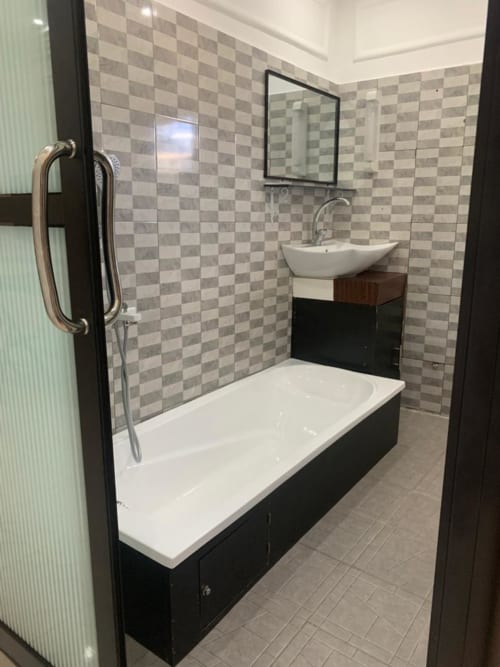 Salle de bains moderne de la Mini-suite F7 à l'hôtel Ôkèrè Ôburu, Lomé avec vasque blanche, baignoire et carrelage à carreaux