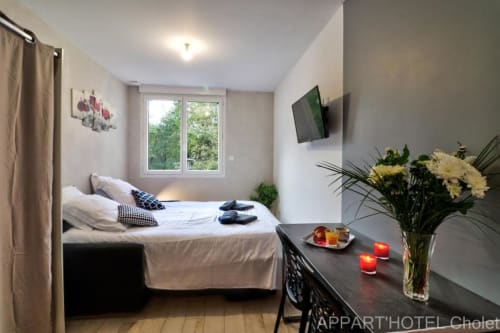 Studio moderne à l'Appart'Hôtel Cholet avec lit, kitchenette, vue sur le jardin, fleurs et bougies