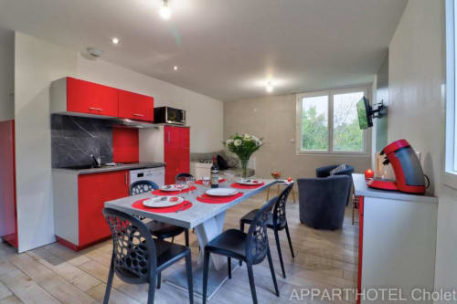 Cuisine-salle à manger moderne rouge et noir à l'Appart'Hôtel Cholet avec table et places assises