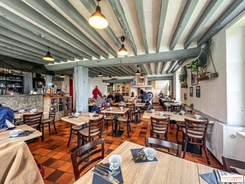 Sala da pranzo del Relais Saint-Laurent a Chevreuse con tavoli in legno, sedie a righe, travi a vista e illuminazione a sospensione