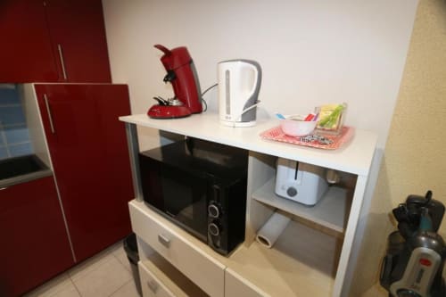 Coin cuisine avec cafetière rouge, bouilloire blanche, micro-ondes et électroménagers divers dans l'appartement de l'Appart'Hôtel Cholet