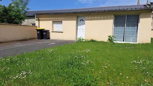 Yellow villa exterior with manicured garden and white door at Appart'Hôtel in Cholet, France