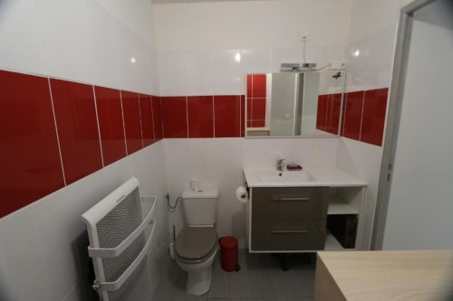 Modern bathroom in Appart'Hôtel villa with red and white tile walls, vanity sink, toilet, and heated towel rack in Cholet.
