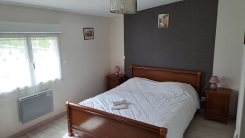 Spacious bedroom in Appart'Hôtel villa, Cholet with wooden bed, dark accent wall, and garden view windows