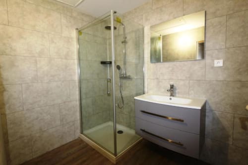 Salle de bain moderne à l'Appart'Hôtel villa de Cholet avec douche vitrée, vasque blanche et murs carrelés beige