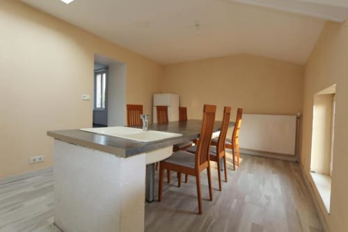 Salle à manger moderne dans villa 3 chambres à Appart'Hôtel Cholet avec chaises en bois, îlot de cuisine et vue sur le jardin