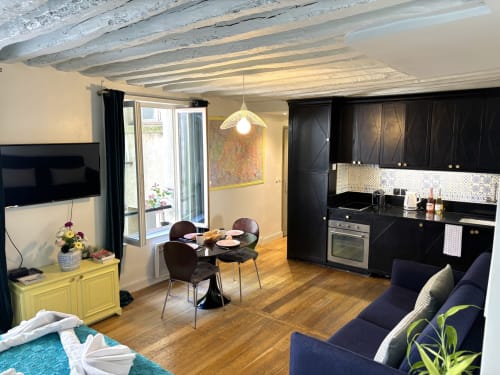 Moderno apartamento parisino con cocina negra, comedor y sofá azul cerca del Louvre