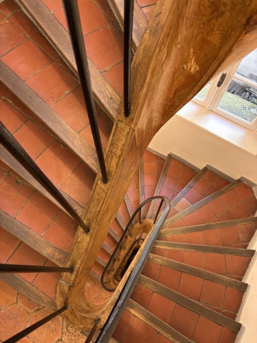 Escalera de caracol de madera con peldaños de baldosa terracota en el apartamento ALDARO, París 7