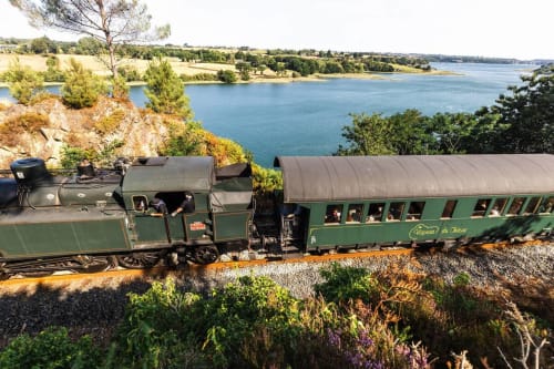 Train à vapeur vert vintage avec passagers voyageant le long de la voie ferrée côtière pittoresque près du Gîte de Ker Huon à Runan, France