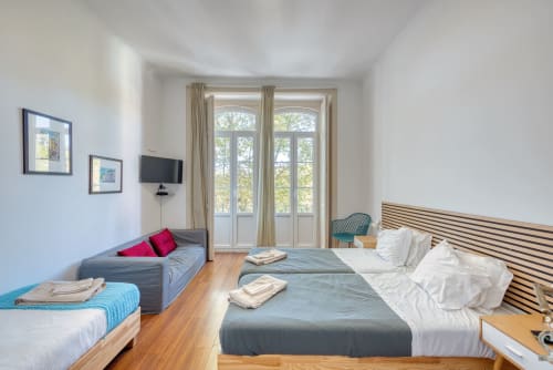Quarto luminoso em Monte da Lua, apartamento Sintra com várias camas, piso em madeira e vista para montanha através de portas francesas