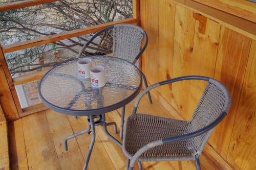 Patio con vista al jardín del Hotel El Porvenir con sillas de mimbre, mesa redonda y tazas sobre terraza de madera