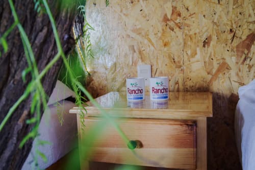 Botellas de Rancho La Providencia en repisa de madera con plantas verdes en la villa del Hotel El Porvenir