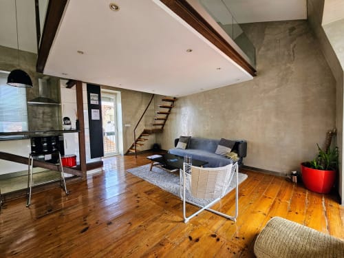 Loft moderno em Lisboa com sala integrada, cozinha, piso em madeira, sofá e escadas para mezanino