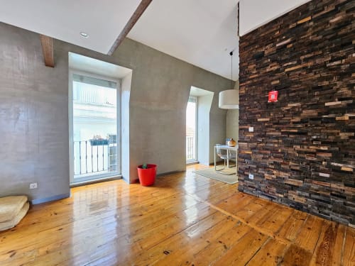 Moderno apartamento loft em Lisboa com assoalho em madeira, parede de tijolos aparentes e varanda com vista para a cidade