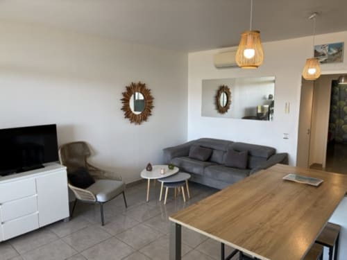 Soggiorno moderno a Porticcio con tavolo da pranzo, divano grigio, televisione e specchi decorativi