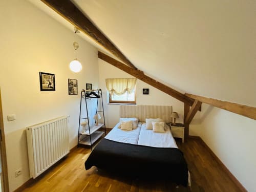 Chambre mansardée douillette à La Conciergerie des Lacs à Gérardmer avec poutres apparentes, lit double et vue sur le jardin