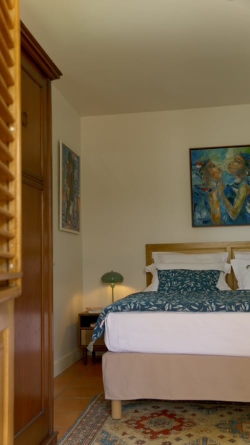 Chambre moderne du FORTY PALMS BnB à Lamentin avec lit en bois, parure bleue motifs, œuvres d'art et éclairage chaleureux