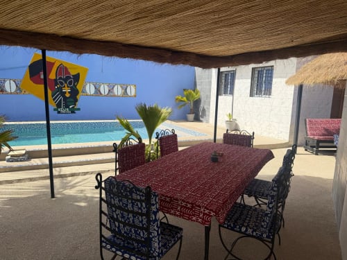 Zone de restauration ombragée au Keur Medzo avec piscine et bâtiment bleu surplombant le Lac Rose à Niaga, Sénégal