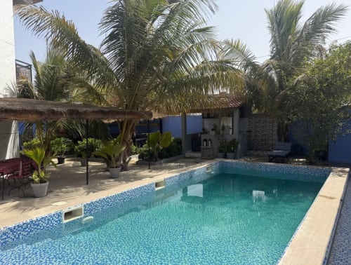 Piscine du gîte Keur Medzo à Lac Rose, Sénégal avec palmiers et pavillon à toit de chaume