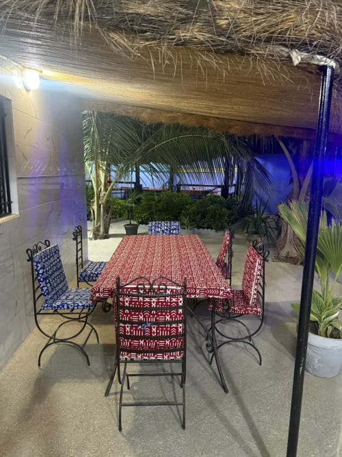 Espace de restauration en plein air chez Keur Medzo avec chaises à motifs et table sous toit en chaume de palmier, Lac Rose