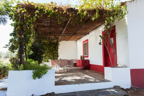 Casa 1 villa em Casas de Juromenha com fachada branca com detalhes vermelhos, pérgola coberta de videiras e terraço de jantar em Juromenha