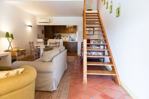Sala de estar de villa moderna em Casas de Juromenha com sofá creme, escada de madeira e cozinha aberta em Juromenha, Portugal