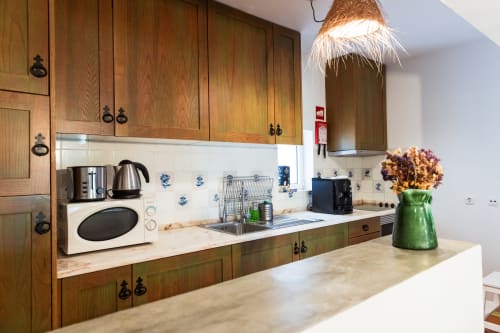 Cozinha moderna na villa Casas de Juromenha com armários de madeira, bancadas de mármore, eletrodomésticos em aço inoxidável e verde