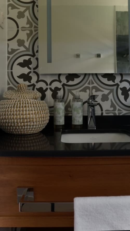 Meuble vasque de la villa FORTY PALMS à Lamentin avec dosseret carrelé noir et blanc et décoration en paniers tressés
