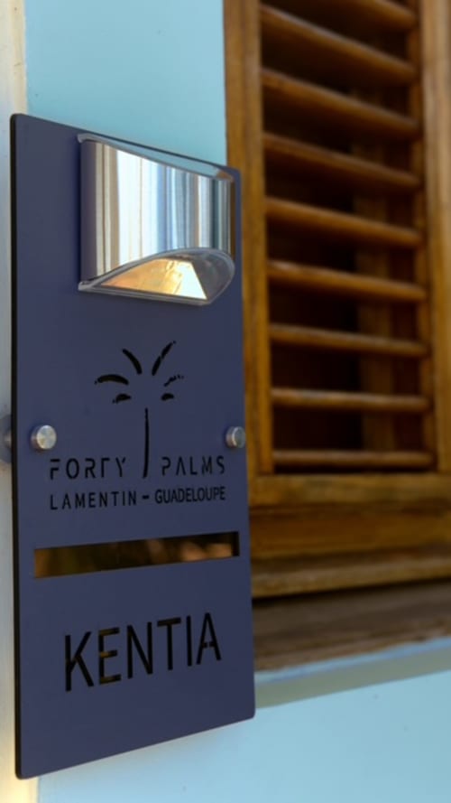 Panneau de chambre de l'hôtel Forty Palms à Lamentin, Guadeloupe avec porte à persiennes en bois et applique murale