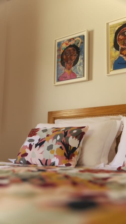 Chambre du lodge FORTY PALMS avec art encadré coloré, coussin à motifs et tête de lit en bois à Lamentin, Guadeloupe