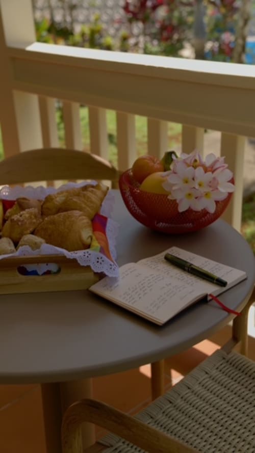 Table accueillante à FORTY PALMS avec pâtisseries, fruits frais, carnet et fleurs surplombant la piscine
