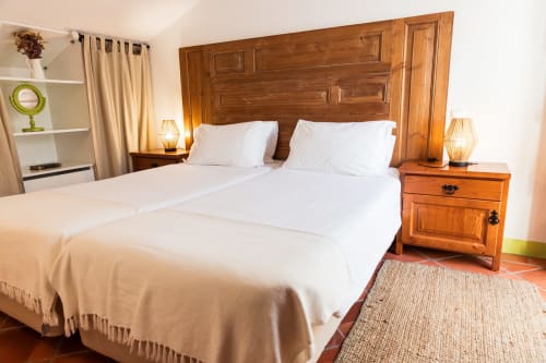 Quarto espaçoso na villa Casas de Juromenha com cabeceira de madeira, roupas de cama brancas e criados rústicos com luminárias