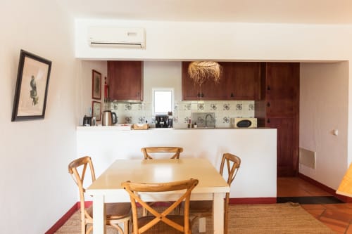 Área de sala de jantar e cozinha em plano aberto na villa Casa 3 em Casas de Juromenha, com cadeiras de madeira, mesa clara e bem equipada