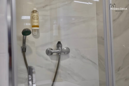 Banheiro moderno com revestimento em mármore, chuveiro manual e dispensador de amenidades no SM Stays Collection em Guarda