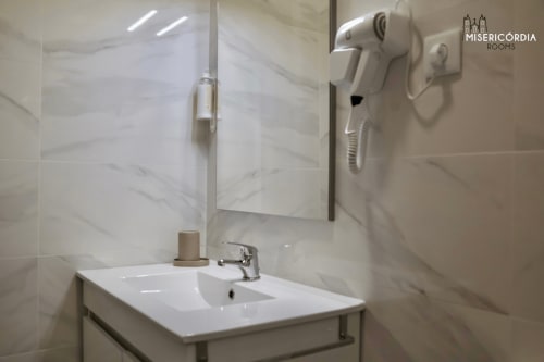 Casa de banho moderna na suíte Portas Del Rei do hotel SM Stays Collection em Guarda, com azulejos de mármore, lavatório branco, espelho e acessórios