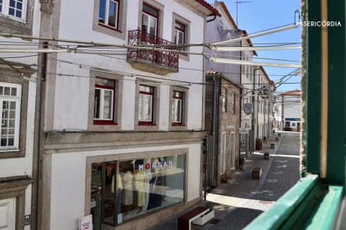 Rua histórica de paralelepípedos em Guarda, Portugal com edifícios brancos tradicionais, fachada da loja Morgan e céu limpo